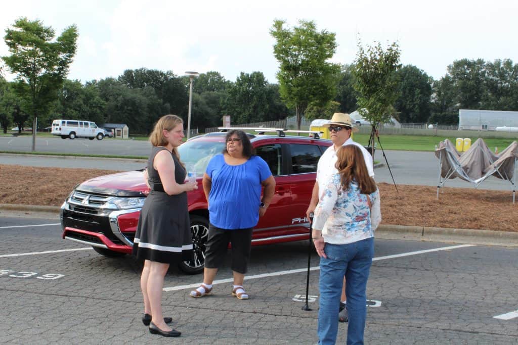 Four people standing around a car