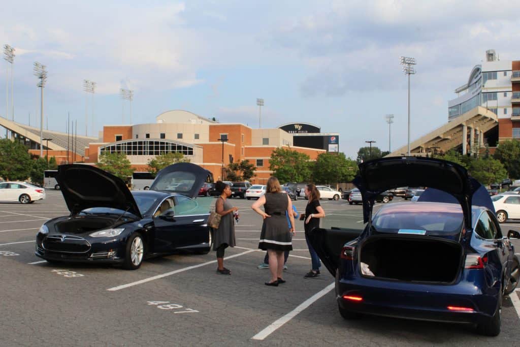 Four people standing between two cars