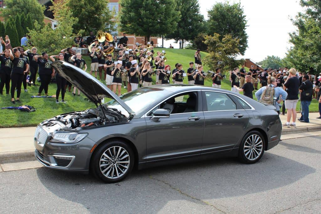 A car with a crowd of people behind it